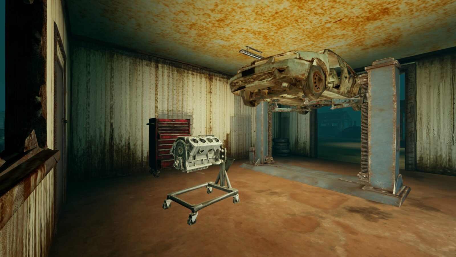 Inside the auto wreckers' bay: a stripped car raised on the two-post hoist, an engine on a stand and a red toolbox beside it, the garage door open to the night